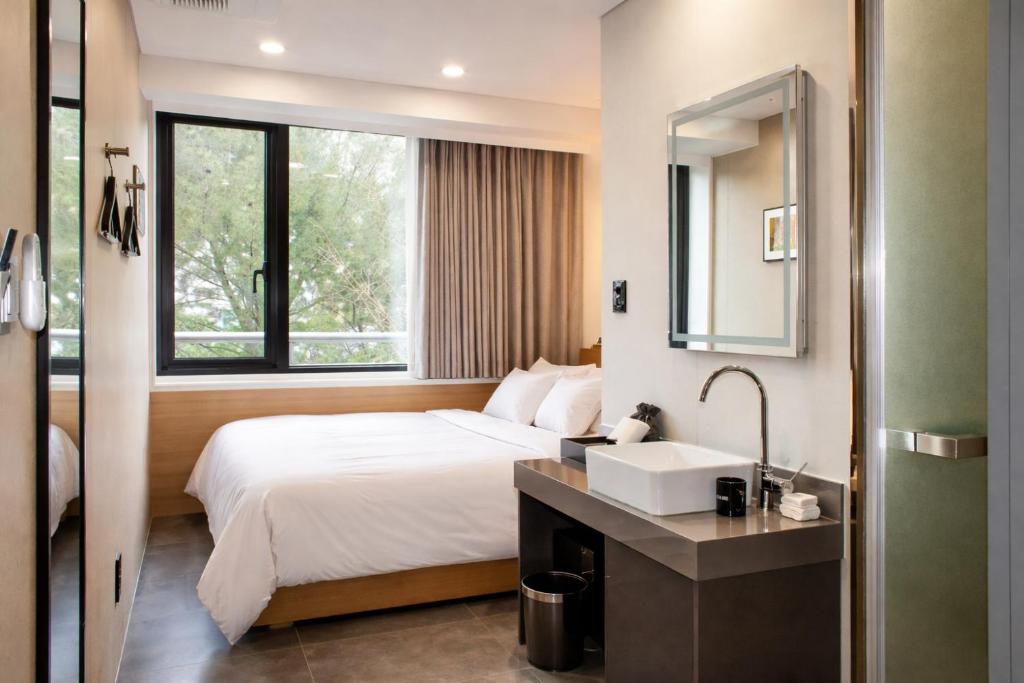 a bedroom with a bed and a sink and a mirror at JE JA RI Stay in Seoul