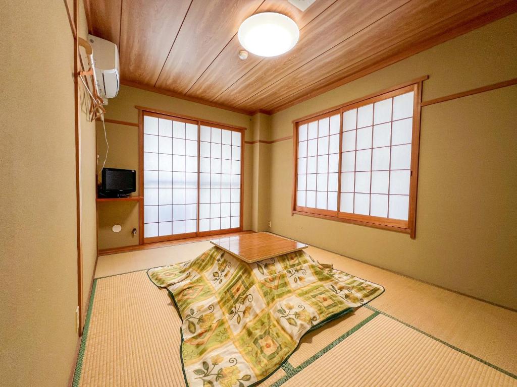 a room with a table in the middle of a room with windows at Chouchinya in Nozawa Onsen