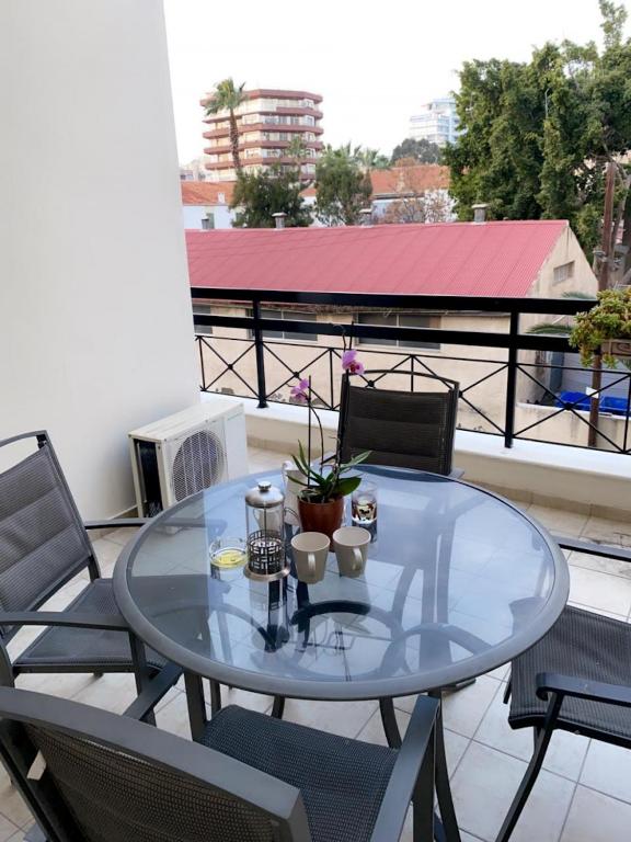 a glass table and chairs on a balcony at Larnaca Beach Apartment in Larnaca