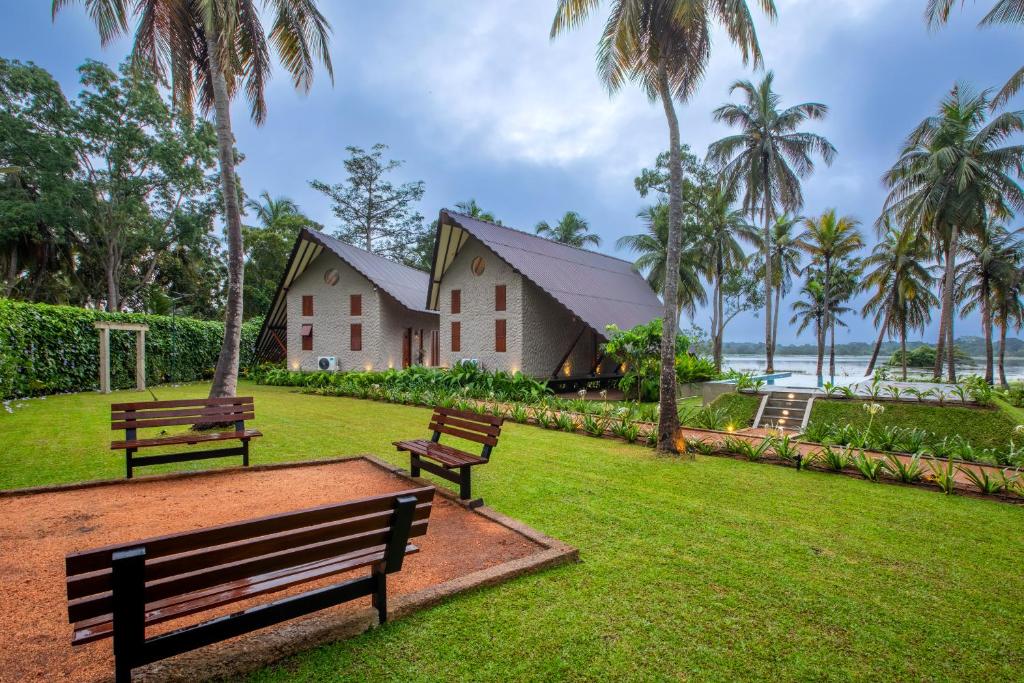 a park with two benches and a building with palm trees at Avora Lake Villas in Anuradhapura