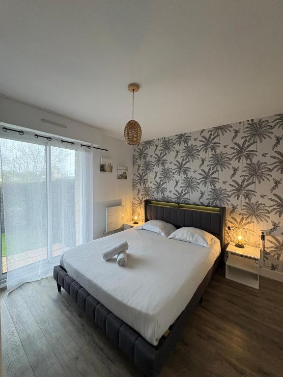 a bedroom with a large bed and a large window at Appartement 200m plage Dinard in Dinard