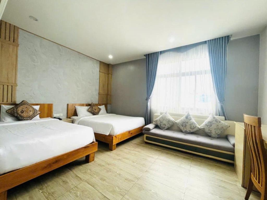 a bedroom with two beds and a couch and a window at Hotel Hoài Bảo in Ấp Rạch Mẹo
