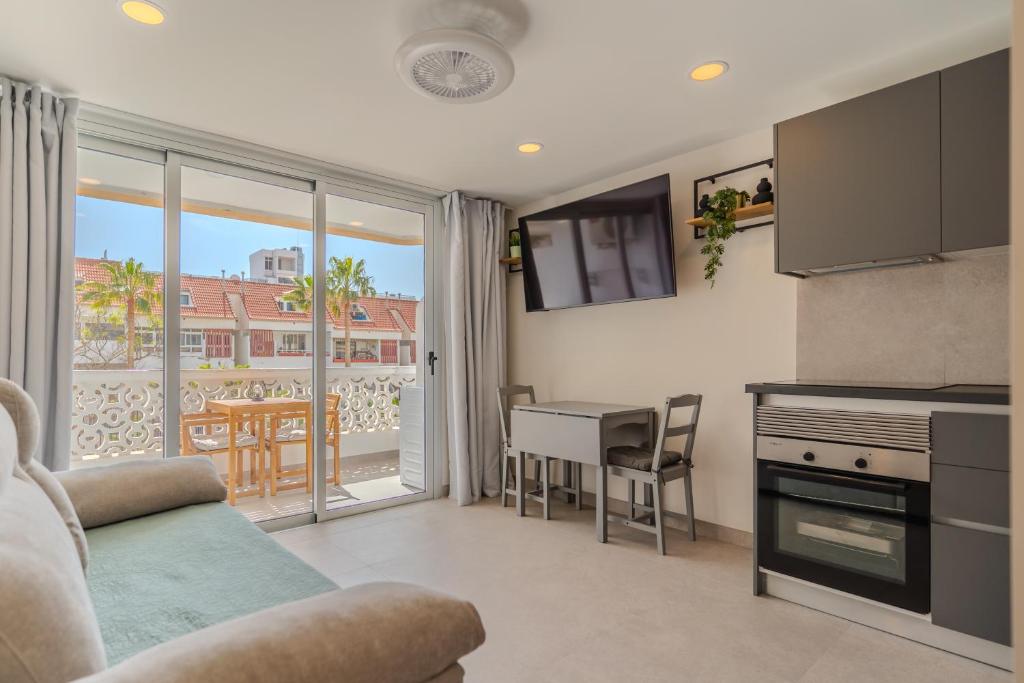 a living room with a kitchen and a table with chairs at Playa Honda Design, Comfort & Pool in Playa de las Americas