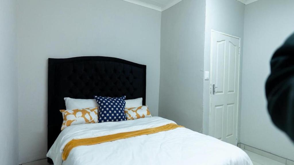 a bedroom with a bed with a black headboard and pillows at Deluxe on Main in Roodepoort