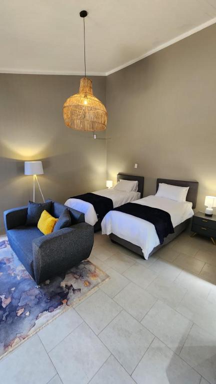 a bedroom with two beds and a couch and a chandelier at 14 on Maroela in Polokwane