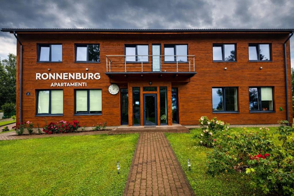a brick building with a sign on the front of it at Ronnenburg apartamenti in Rauna