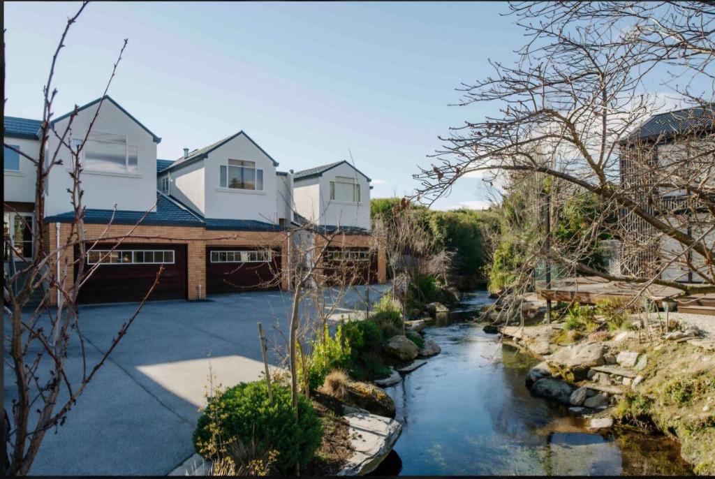 a house with a river in front of it at Cozy Escape in Wanaka