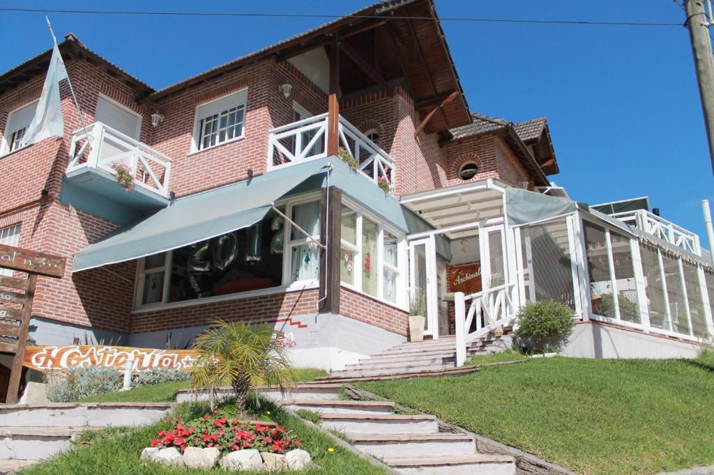 a large brick house with a porch and flowers at Hostería Anchimalen in Villa Gesell