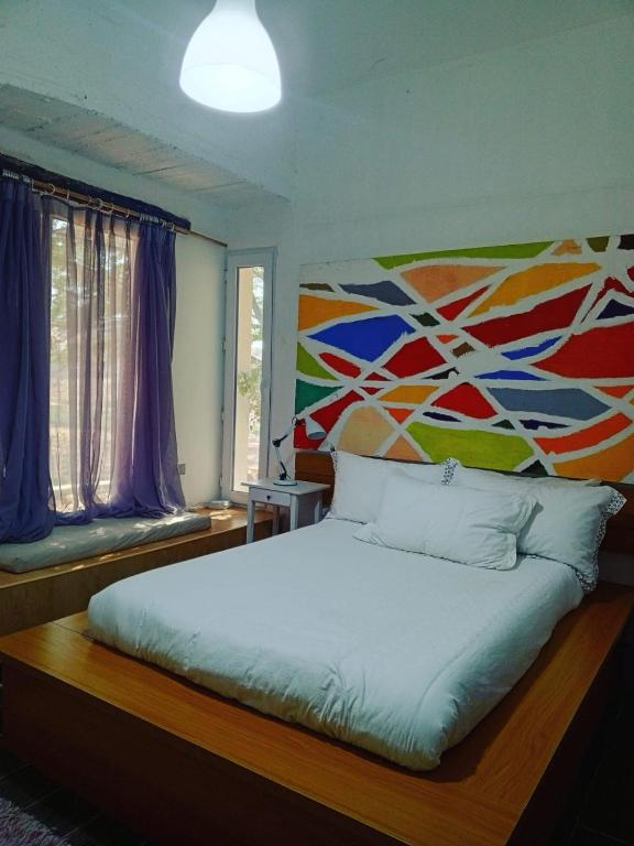 a bedroom with a bed with a painting on the wall at Greek Style Bed & Breakfast in Al Manashsh