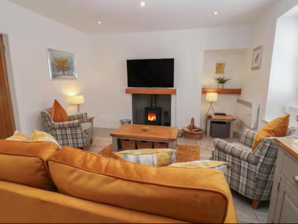 a living room with a couch and a fireplace at Bumblebee Cottage, Aysgarth Falls in Aysgarth