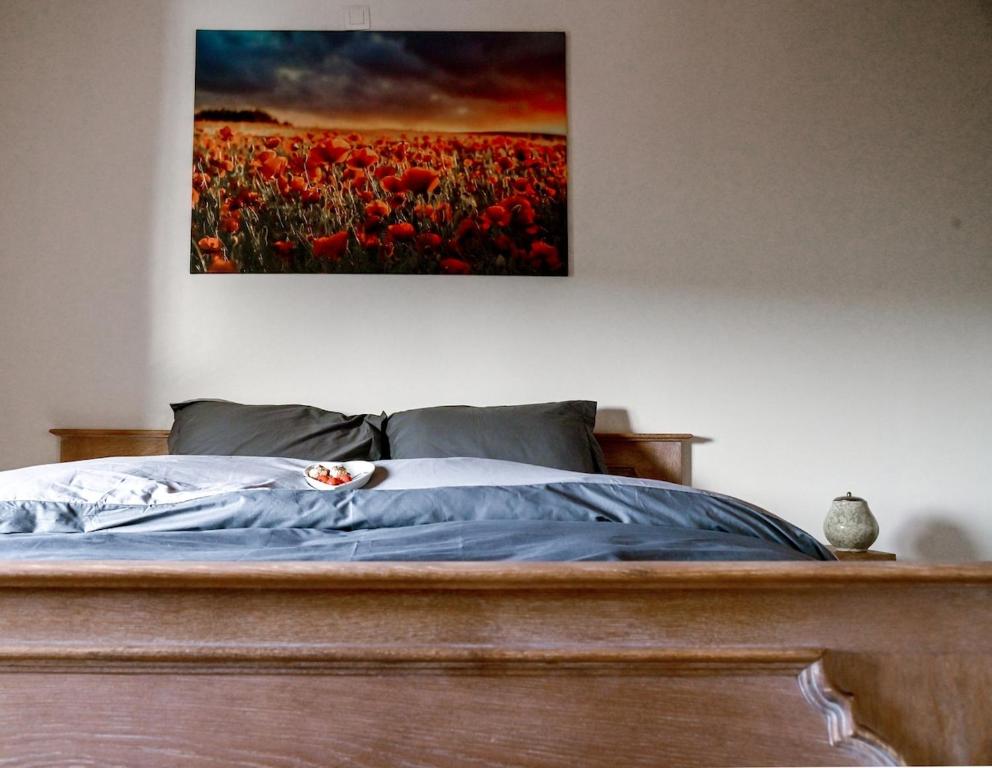 a bedroom with a bed with a painting on the wall at Cosy farmhouse with sauna in Sint-Truiden