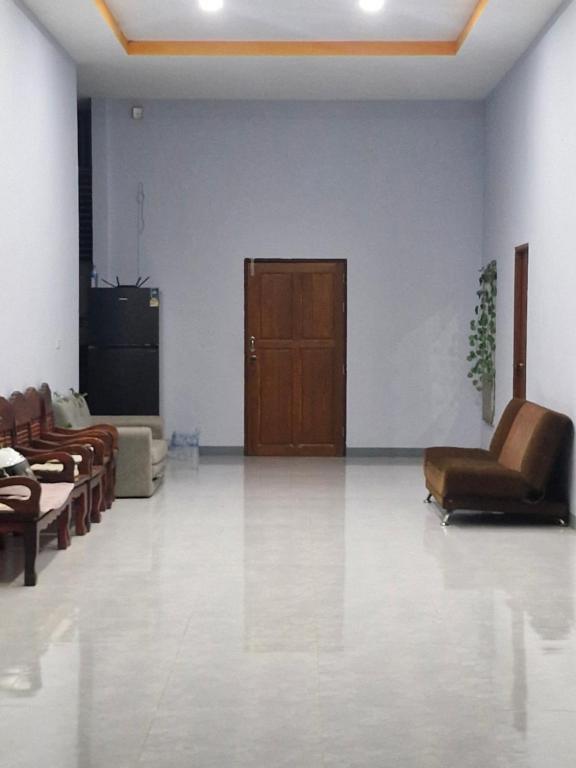 a living room with brown leather chairs and a door at NaklangHillHouse in Ko Lanta Yai