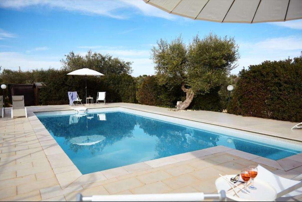a swimming pool in a yard with an umbrella at Trullo Dei Fiori in Cisternino