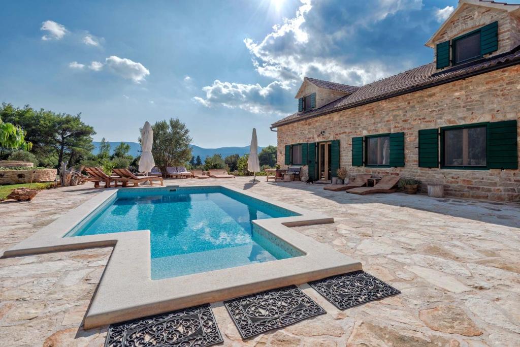 a swimming pool in front of a stone house at Villa Miranda Hvar in Stari Grad