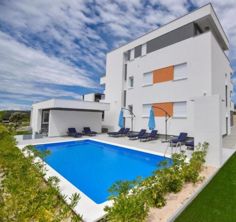 a villa with a swimming pool in front of a building at Pool Apartments & Rooms Mare in Novalja