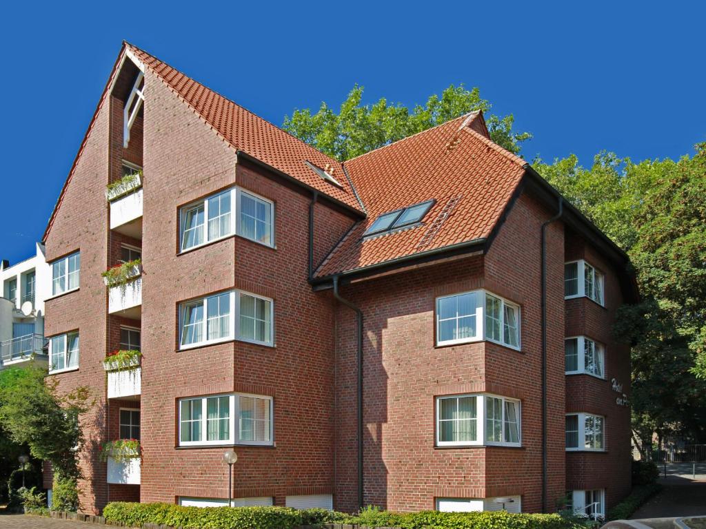 ein Backsteingebäude mit rotem Dach in der Unterkunft Hotel am Park in Dinslaken