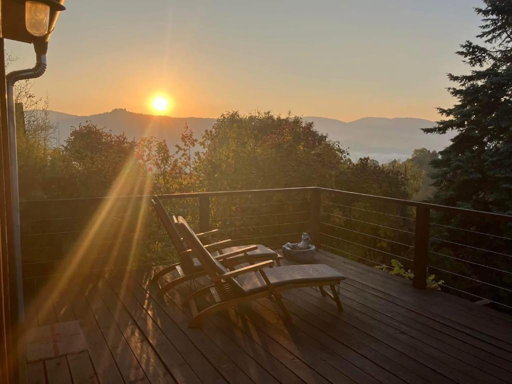 a deck with chairs on it with the sunset in the background at Csillagfény Házikó in Nagymaros