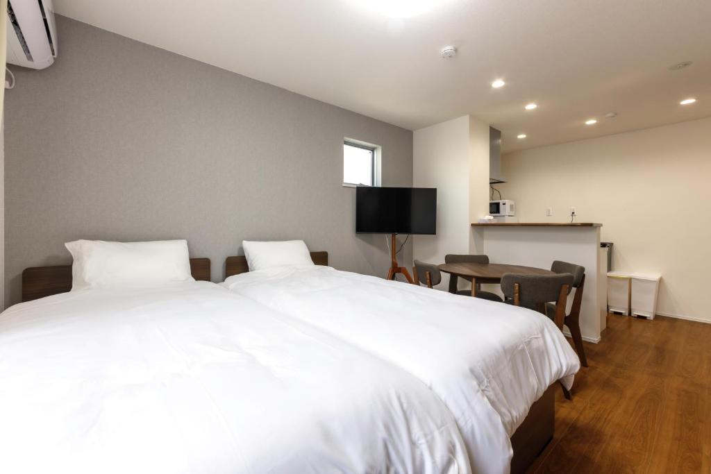a bedroom with a large white bed and a desk at The Top名駅 in Nagoya