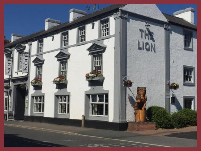 a white building with a lion in front of it at The Lion Hotel in Belper