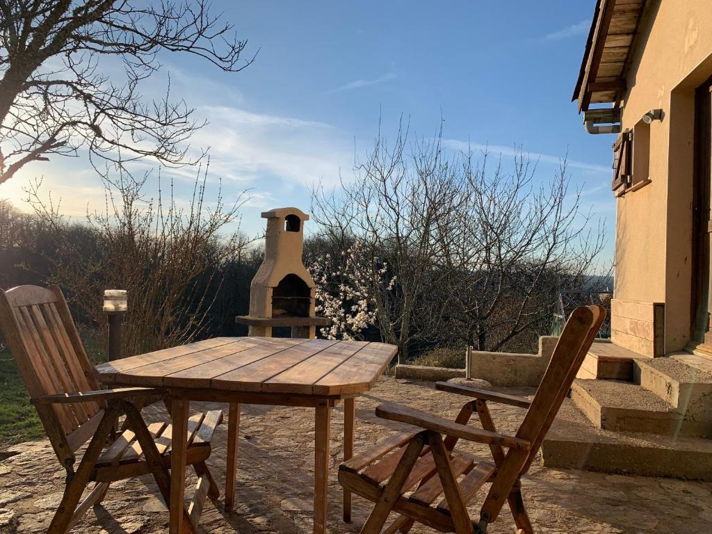a wooden table with two chairs and a stove at Serenane in Saint-André-de-Najac