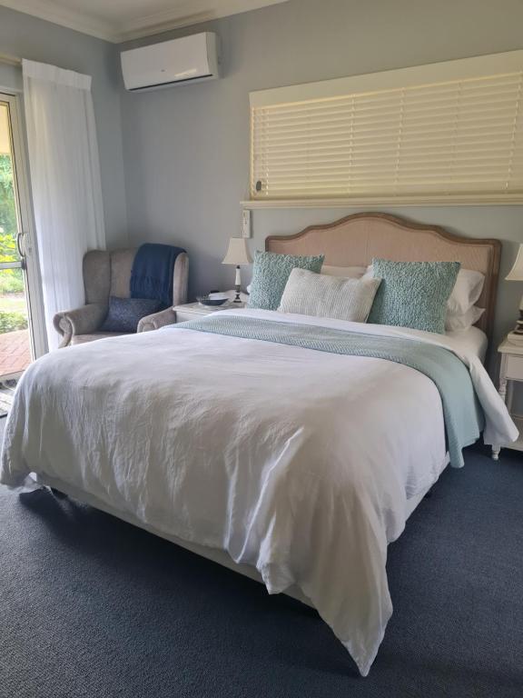a bedroom with a large bed and a chair at Birchwood Gardens Bed and Breakfast in Narrikup