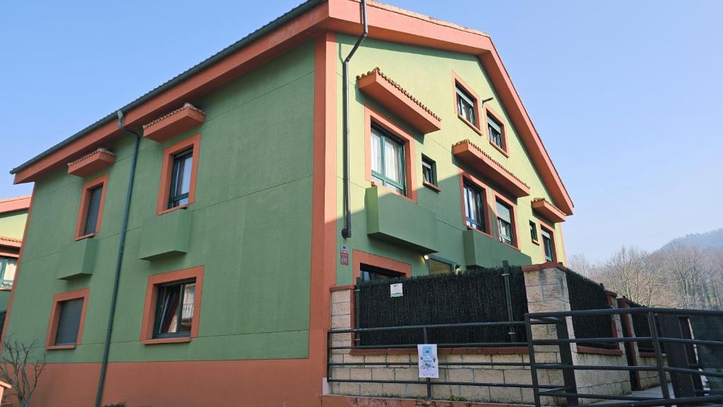 a building that is painted green and orange at Casa Vacacional El Alisu in Arriondas