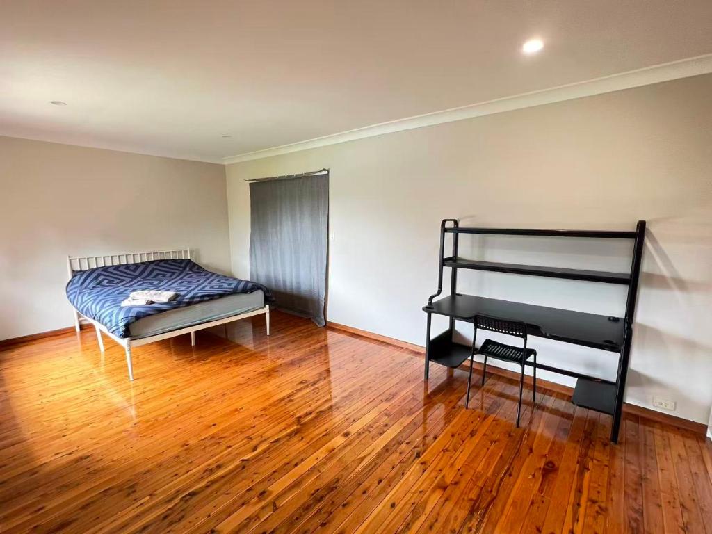 a bedroom with a bed and a wooden floor at Room 44 in Baulkham Hills