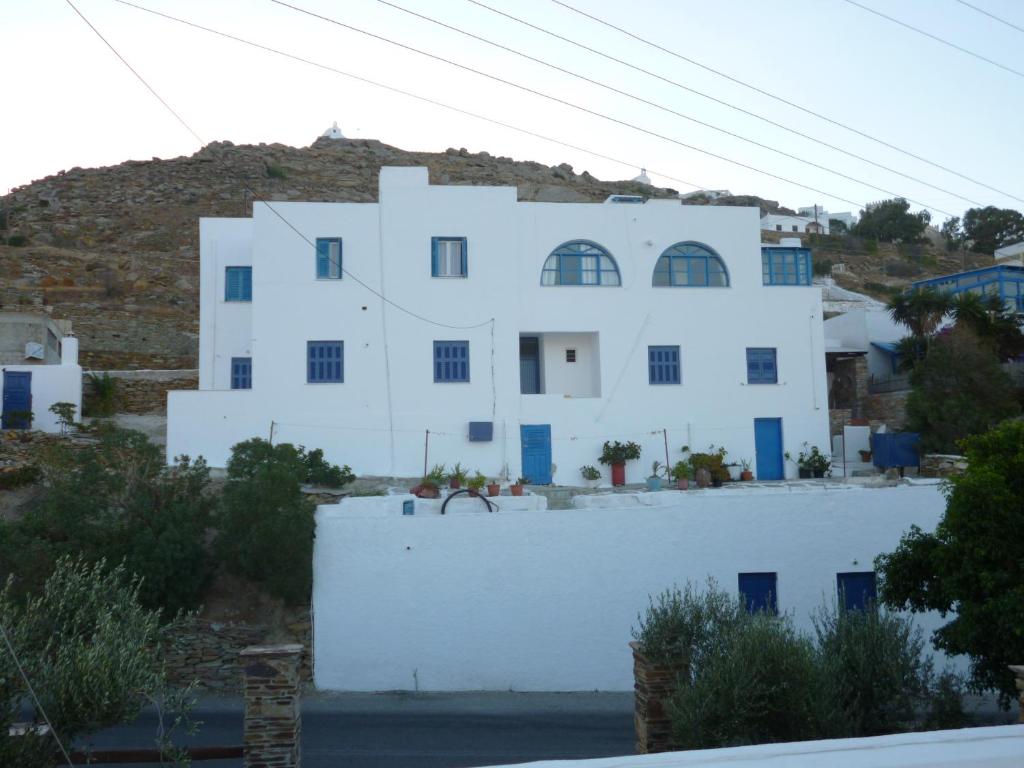 a white house with blue windows and a hill at Vasilis Ios Place II in Ios Chora
