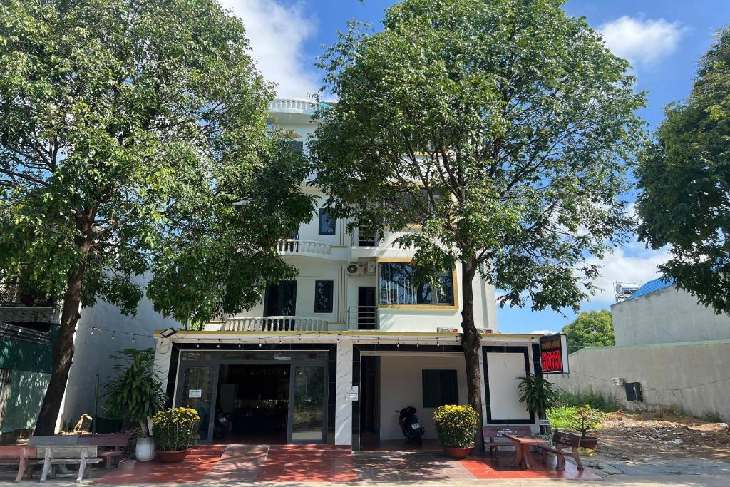a white building with trees in front of it at Thanh Hang Hotel in Ấp Bàu Bàng