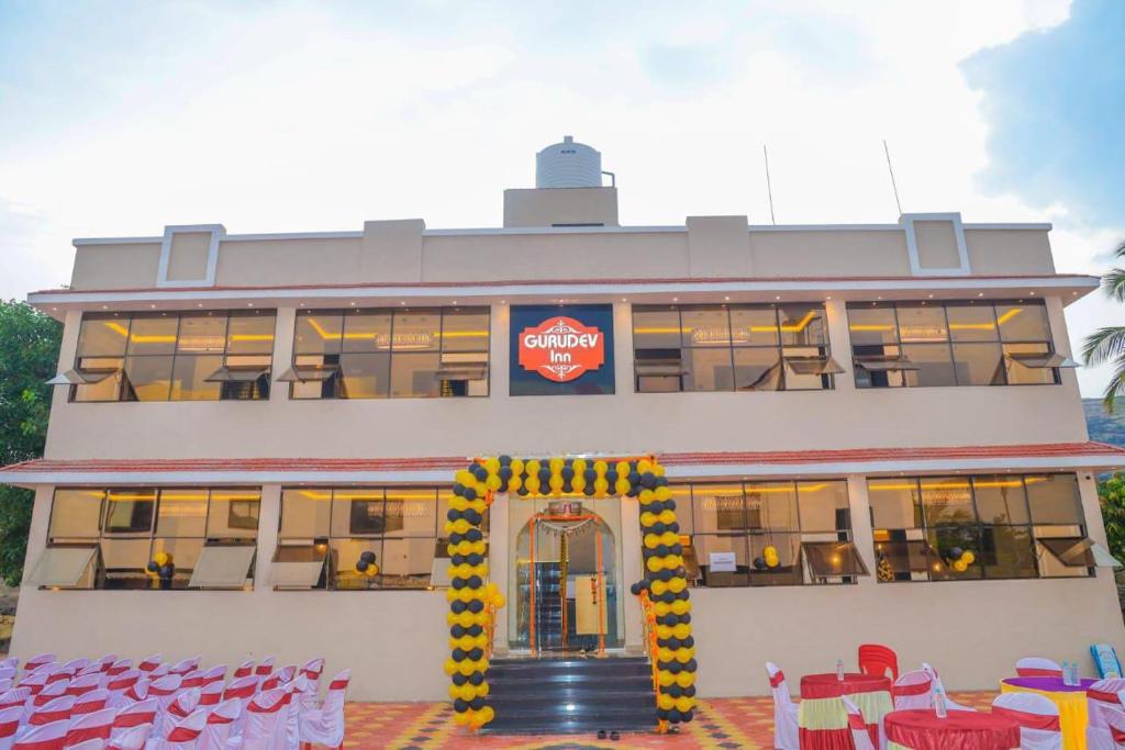 a large building with a lot of windows and red chairs at Hotel Gurudev Inn in Junnar