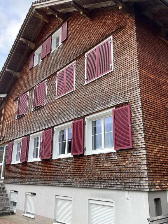 a tall brick building with red shutters on it at GebirgsImker-Apartment in Egg