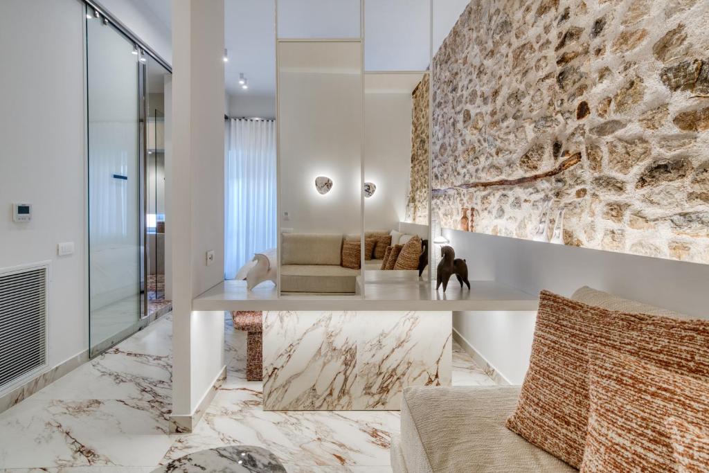 a living room with a couch and a stone wall at Nalia Suites in Nafplio