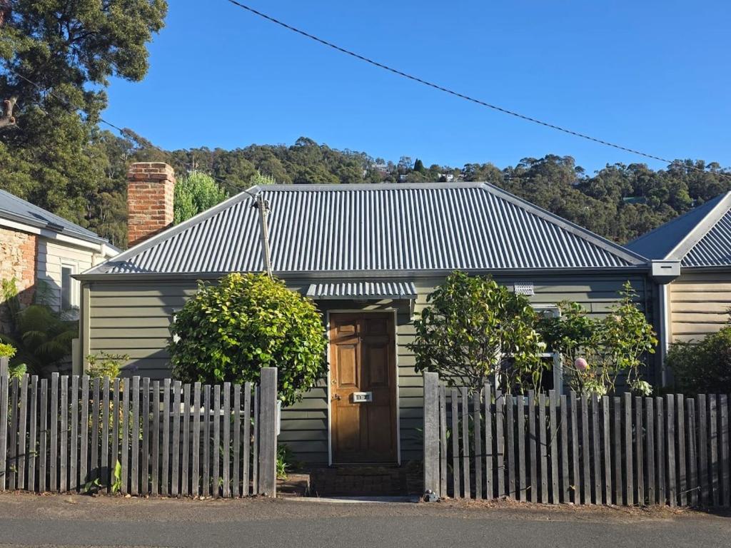 a house with a wooden door behind a fence at Cascade Cottage Circa 1840 in West Hobart
