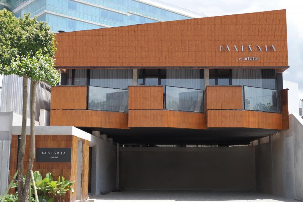 aartment building with a brown building with glass windows at Maisola by ARTOTEL Semarang in Semarang