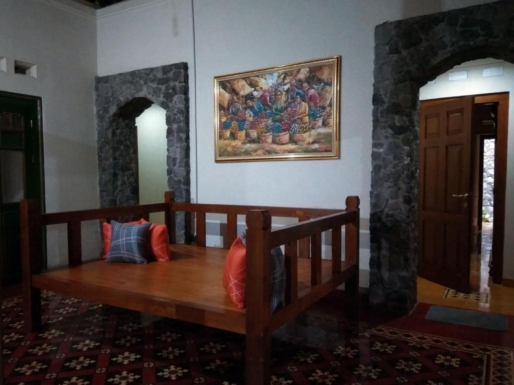 a wooden bench in a room with a painting on the wall at Omah Pitoe Yogya Homestay in Yogyakarta