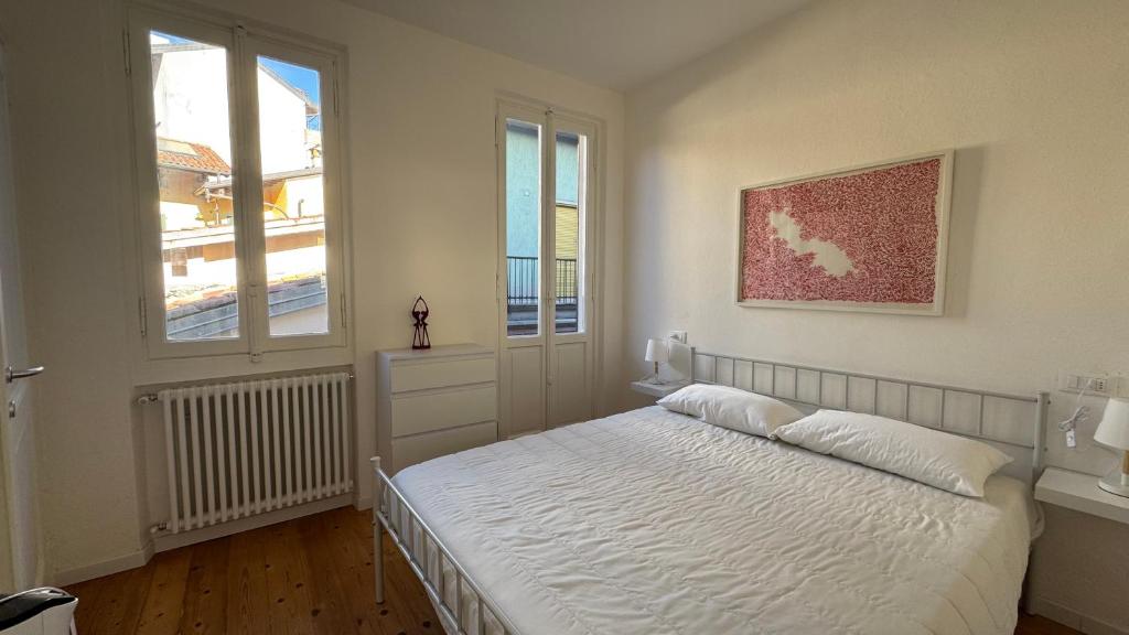 a bedroom with a white bed and two windows at Glicine in Stresa