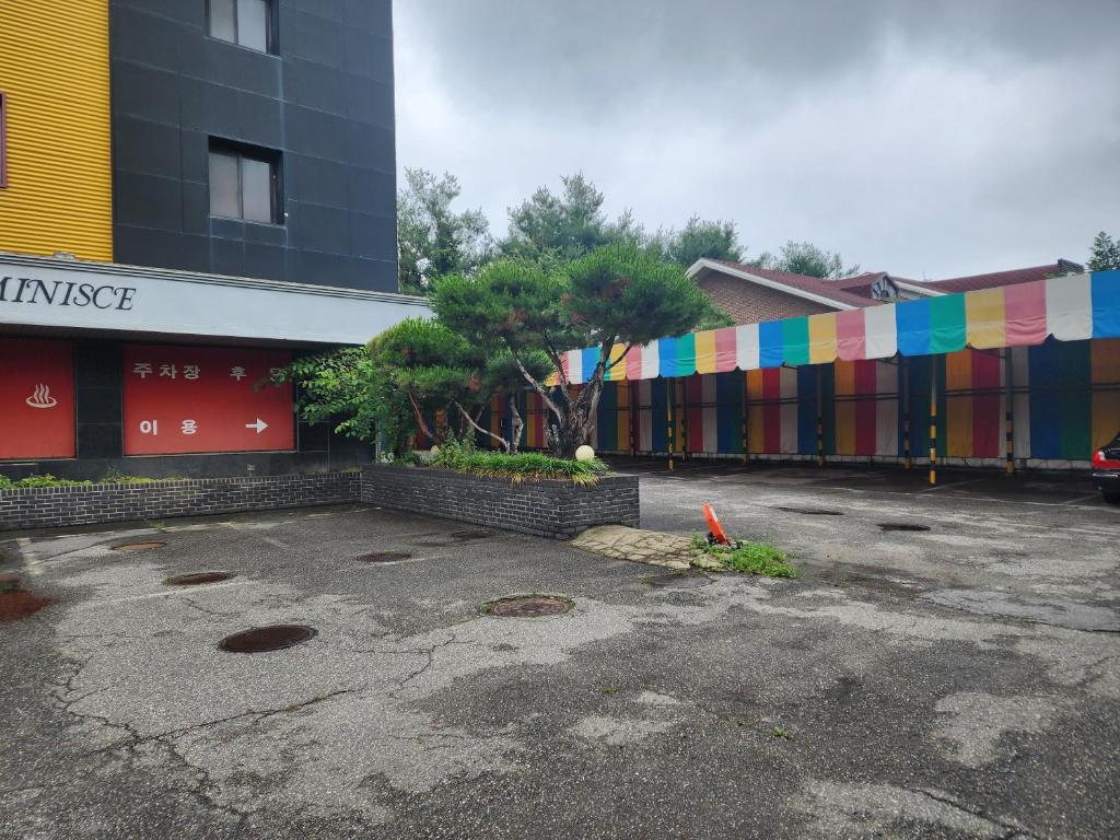 a parking lot with a building with a colorful fence at 레미니스호텔 in Dongtan