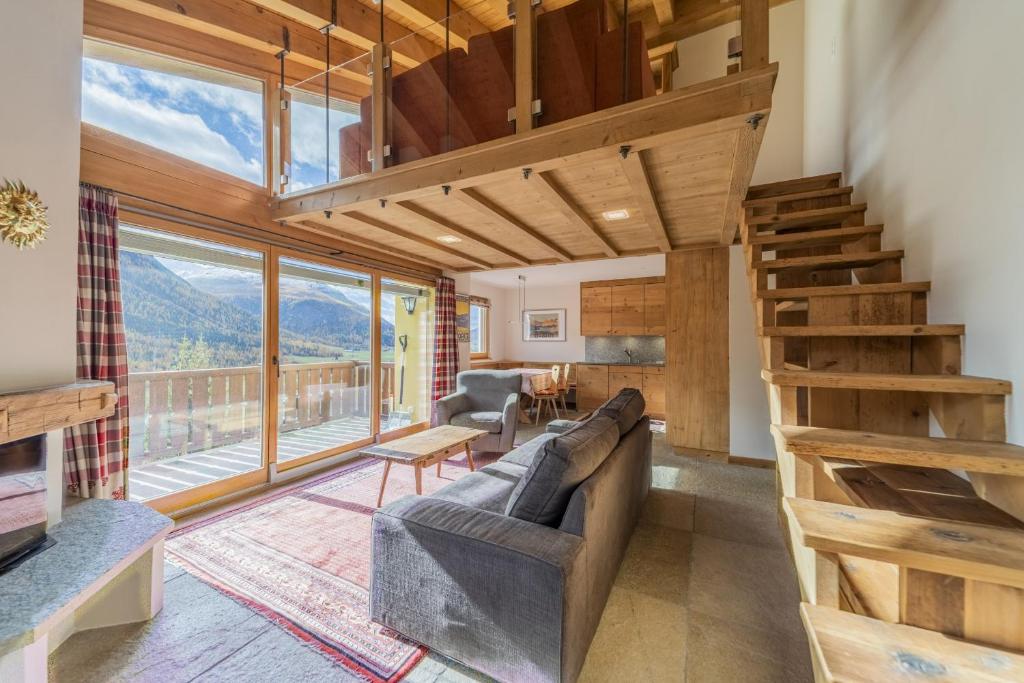 a living room with a couch and a staircase at Chesa Diala - Zuoz in Zuoz