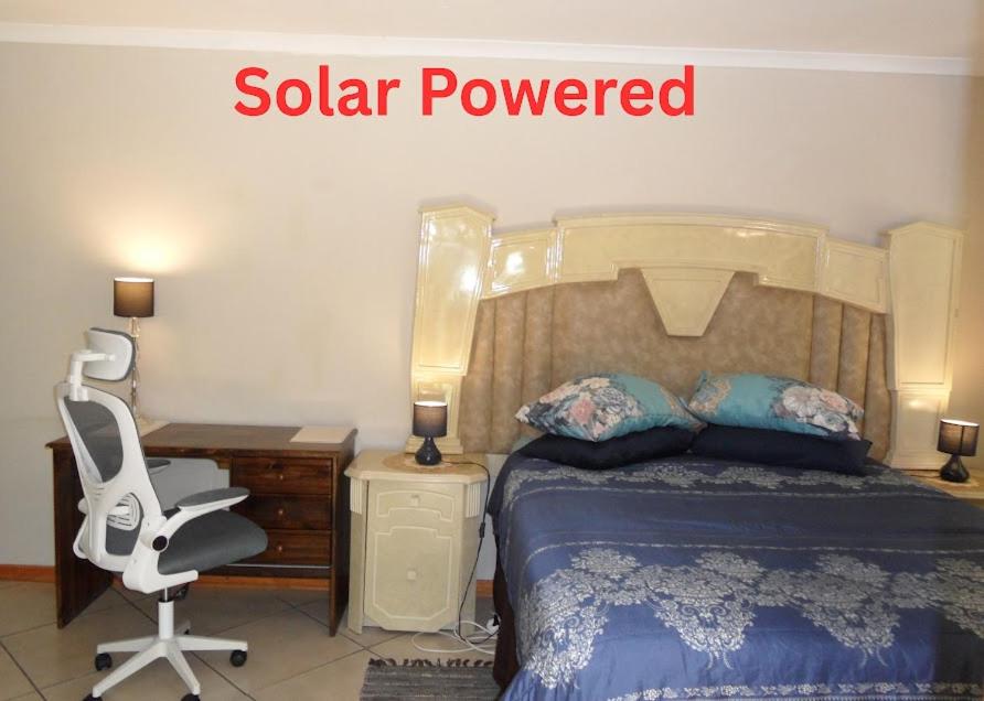 a bedroom with a bed and a desk and a chair at Garden Wing in Upington