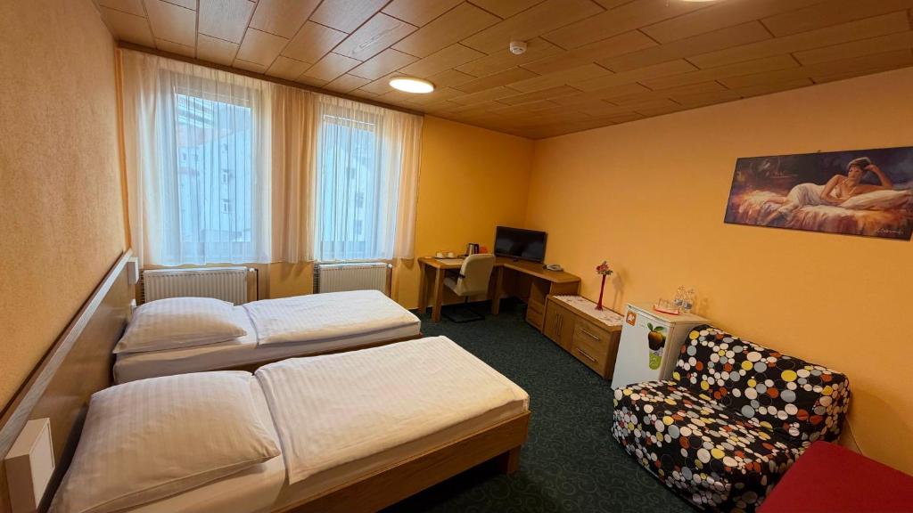 a room with two beds and a couch and a desk at Pension Duel in Ústí nad Labem