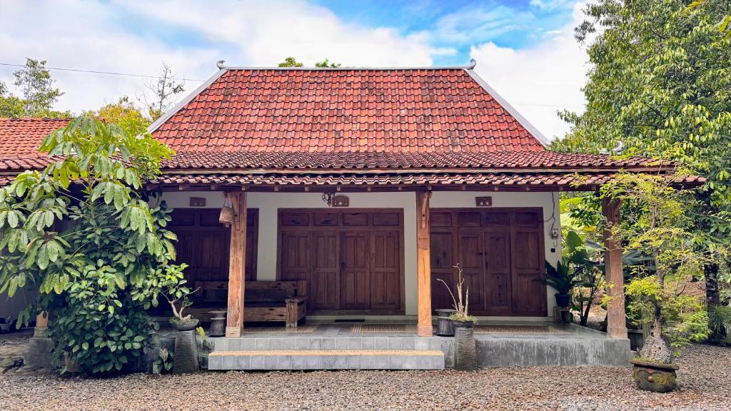 a small white house with a red roof at Omah Ndoro Sugih in Serut