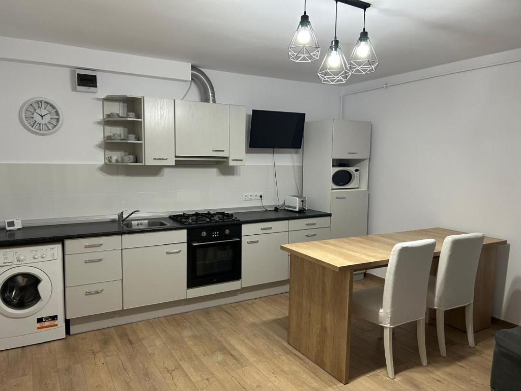 a kitchen with white appliances and a wooden table at Central Apartment in Zalău