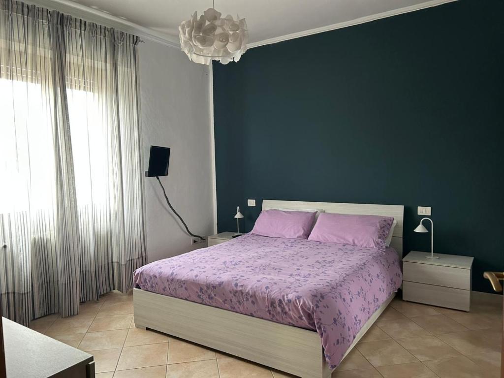 a bedroom with a purple bed and a blue wall at Casa Palma in Rho