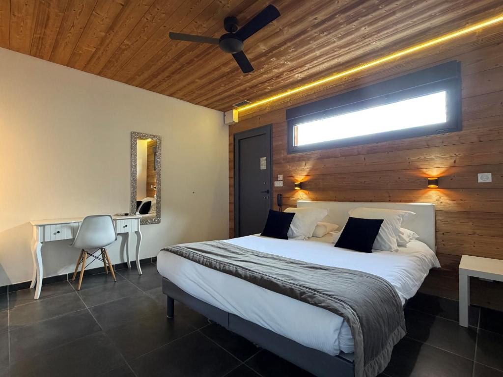 a bedroom with a large bed and a desk at Bio-Motel in Saint-Vulbas