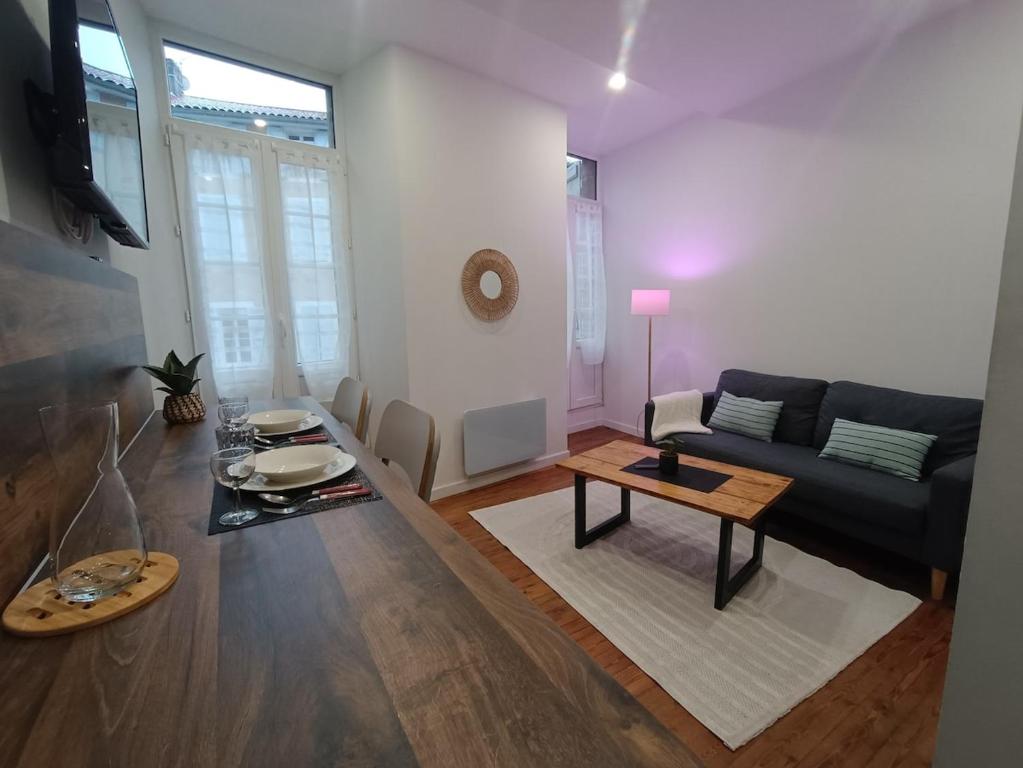 a living room with a black couch and a table at Charmant studio cosy - Hyper centre in Saint-Gaudens