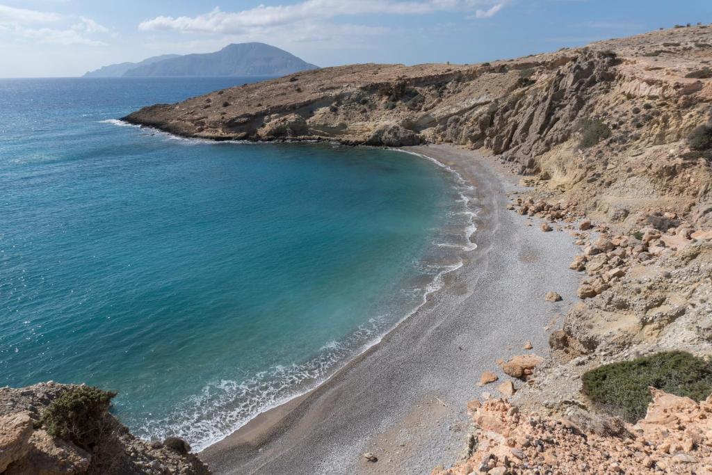 a beach on the side of a rocky mountain at Archipelagos Apartments in Arkasa