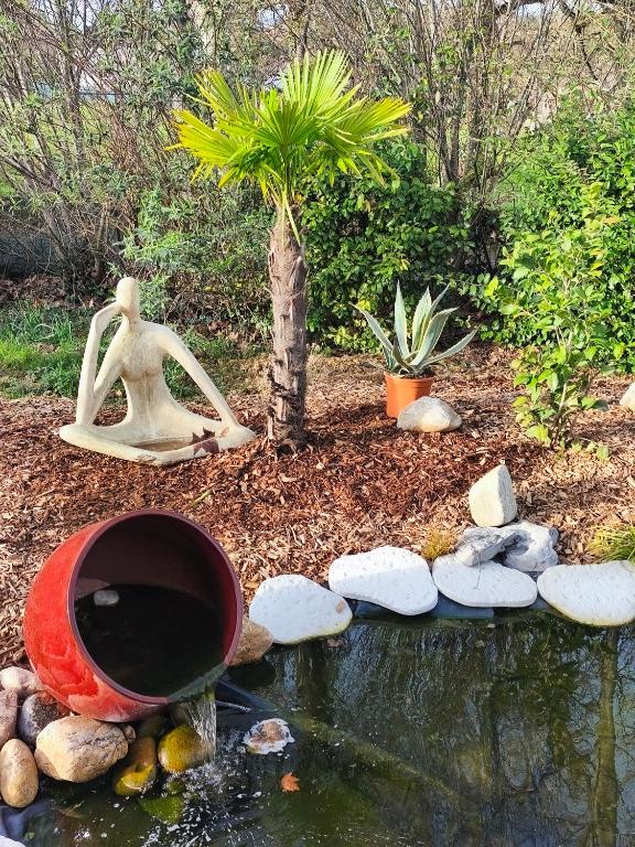 a garden with a woman statue and a pond at Ostal del Koï in Rabastens