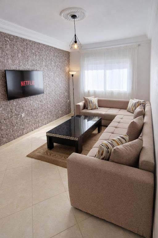 a living room with a couch and a tv at Cozy appartement à Mohammedia in Mohammedia