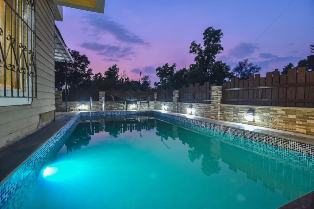 a swimming pool with blue water at night at Klassone Bunglow in Khandāla