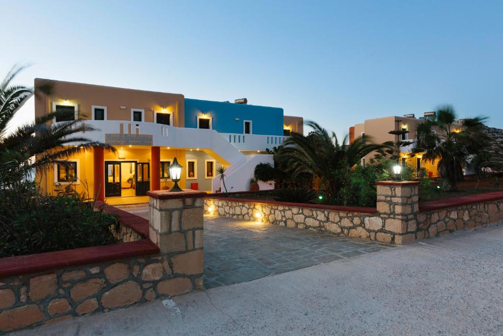 a house with a stone fence in front of it at Archipelagos Apartments in Arkasa